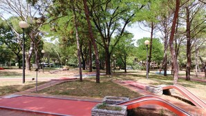 Ein Park mit einem roten Weg, Steinbeeten und Bäumen.