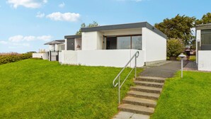A modern two-story house with a white exterior, a front porch, and a staircase leading to the entrance. - 1 bedroom amazing home in Tranekær (Tranekær)