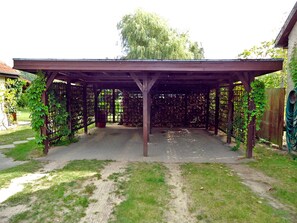 A covered patio area with a pergola structure, surrounded by a wooden fence and a garden. - Holiday house on Klostergrund - holiday home (Malchow)
