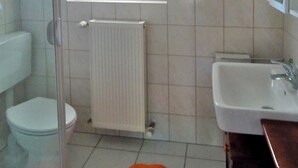 Ein Badezimmer mit Toilette, Dusche, Waschbecken und Handtuchwärmer.