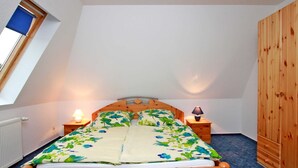 Ein Schlafzimmer mit einem hölzernen Bett, zwei Nachttischen mit Lampen, einer Heizung und einem Holzschrank.
