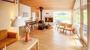 A spacious living room with a wooden floor, a sofa, a dining table, and a fireplace.