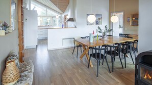 A spacious kitchen with a dining area, wooden flooring, and a fireplace.