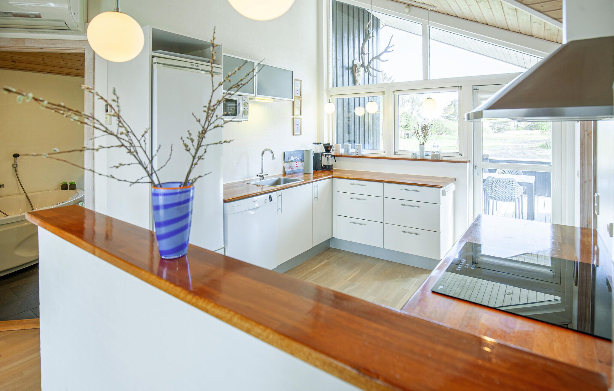 A modern kitchen with a wooden countertop, built-in appliances, and a view of the outdoors.