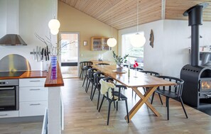 Una cocina moderna con una mesa de madera, sillas, horno empotrado y estufa a leña.