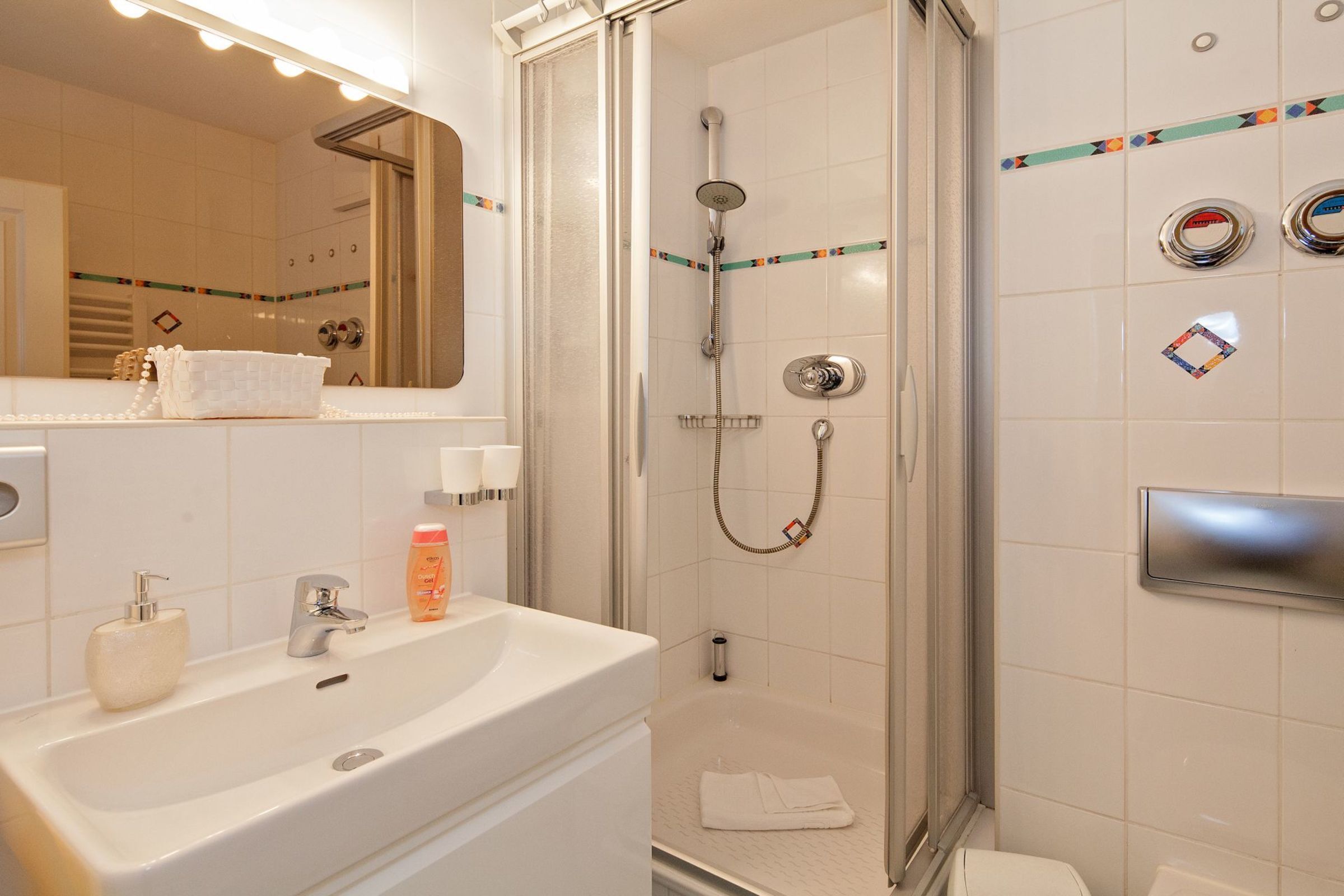 A bathroom with a sink, mirror, shower, and toilet.