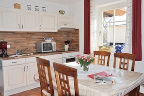 A kitchen with white cabinets, a microwave, a stove, and a dining table with chairs.