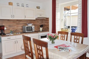 A kitchen with white cabinets, a microwave, a stove, and a dining table with chairs.