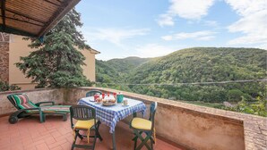 Eine Terrasse mit Tisch und Stühlen für zwei Personen und Blick auf einen bewaldeten Hügel.