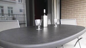 Ein runder Tisch mit dunkler Oberfläche, zwei klare Gläser und eine Wasserflasche.
