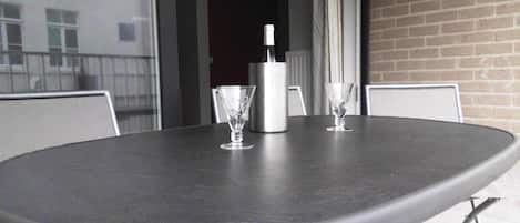 Et rundt bord med mørk overflade, to glas og en vandflaske.