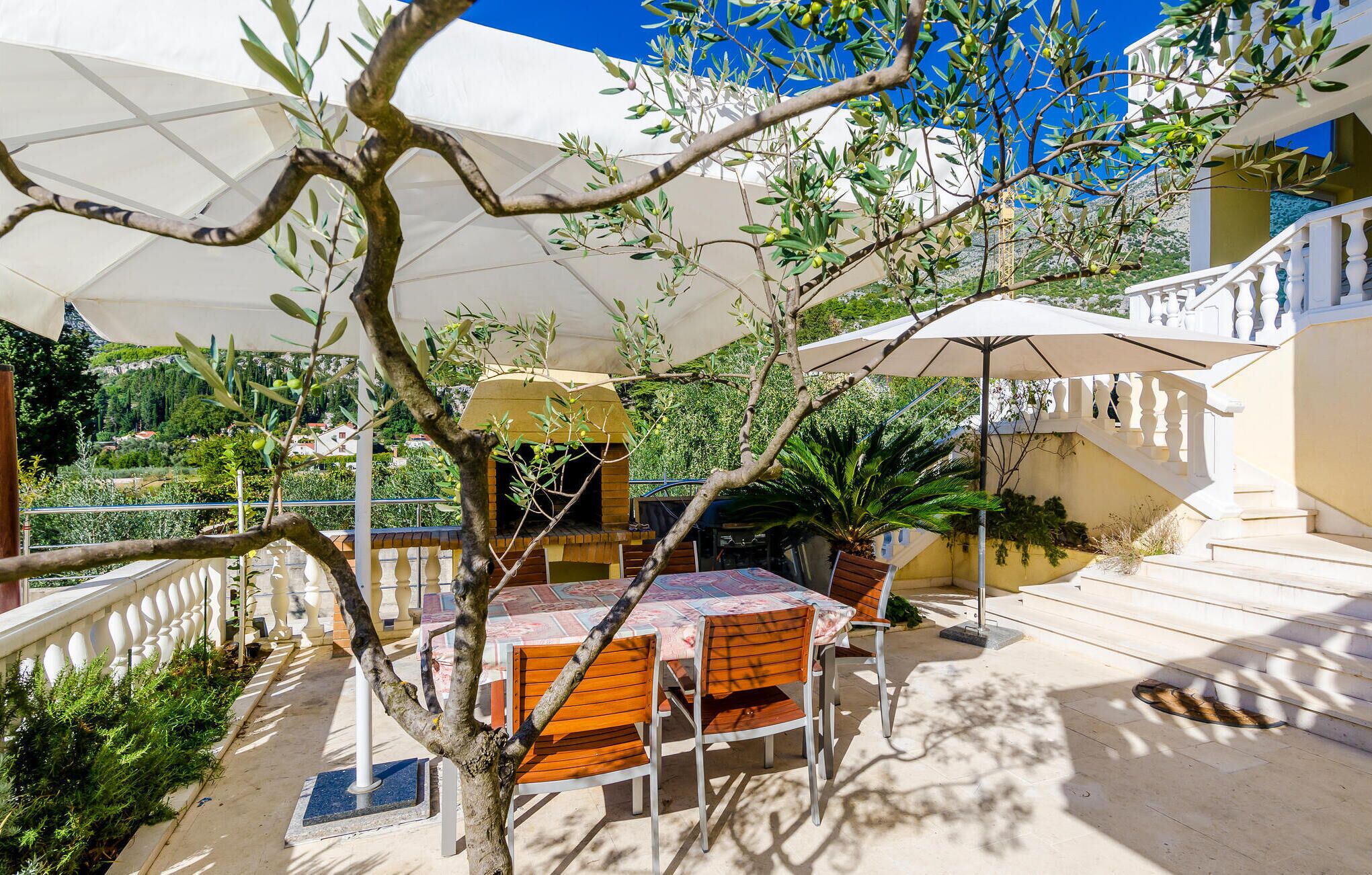 Een buitenterras met tafel en stoelen, omringd door parasols, met uitzicht op een prachtig landschap.