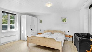 A bedroom with a wooden bed, white walls, a large window, a wardrobe, and a small bedside table with a lamp. - 3 bedroom gorgeous home in Toftlund (Toftlund)