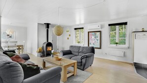 A modern living room with a fireplace, grey sofas, a wooden coffee table, and a dining area with white chairs. - 3 bedroom gorgeous home in Toftlund (Toftlund)