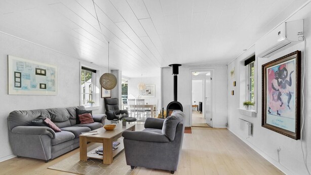 A spacious living room with a grey sofa, a wooden coffee table, and a grey armchair. There is a large window providing natural light and a view of the outdoors. - 3 bedroom gorgeous home in Toftlund (Toftlund)