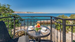 Une table avec vue sur la mer, une chaise et une rambarde.