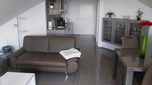 Ein kompakter Wohnraum mit einem braunen Sofa, einem kleinen weißen Tisch und einer Vitrine.
