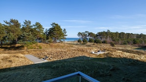A view from a window overlooking a natural landscape with a clear sky, a body of water, and a variety of trees. - Nice apartment in Binz with house sea view (Prora/Rügen)