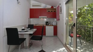 A compact kitchen with red cabinets, a white countertop, and a dining area with two chairs. - Gorgeous apartment in Arbanija with WiFi (Arbanija)