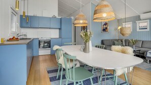 Una cocina moderna con armarios azules, una isla blanca y lámparas colgantes de mimbre.