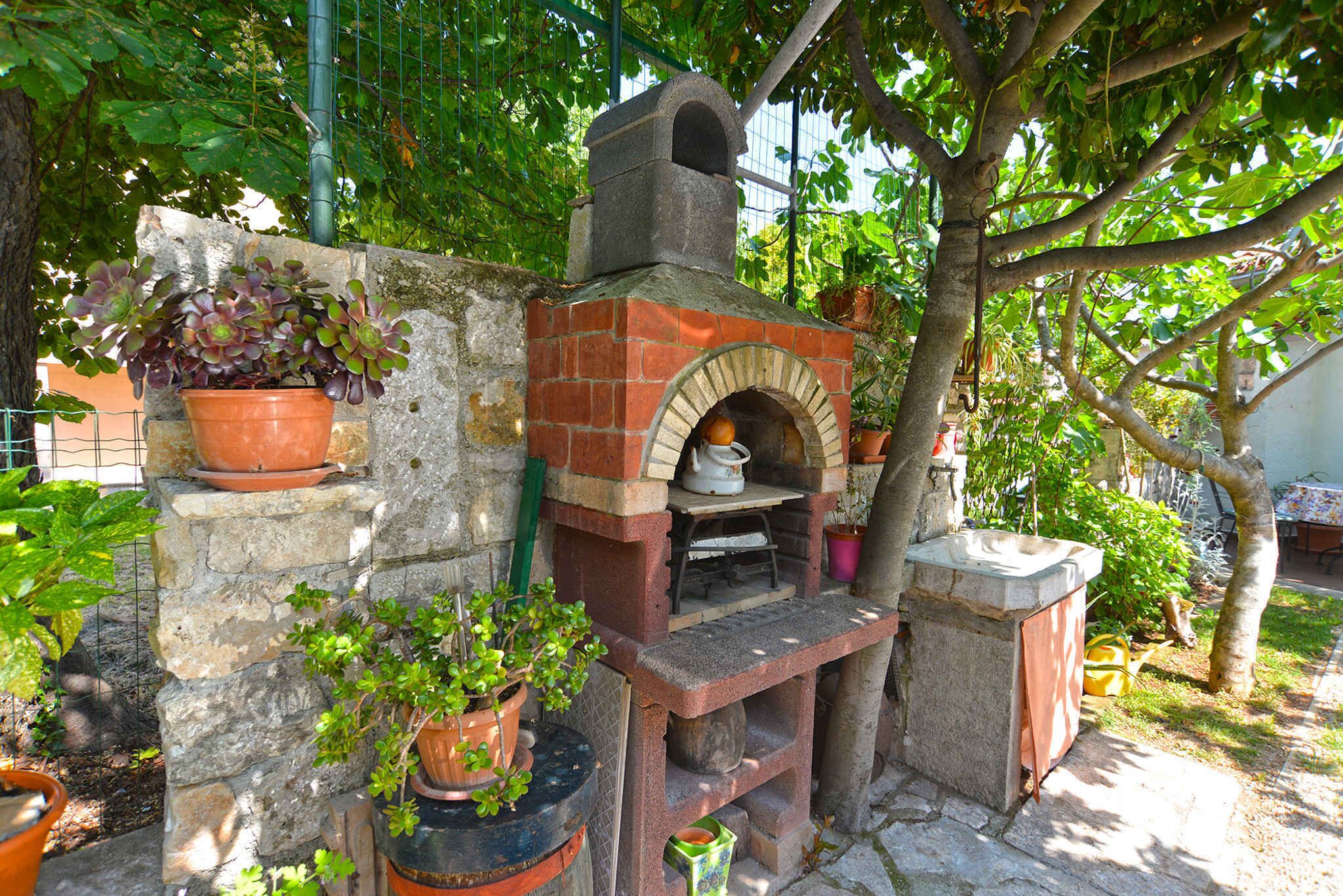 Un four en briques installé à l’extérieur, entouré de plantes en pot.