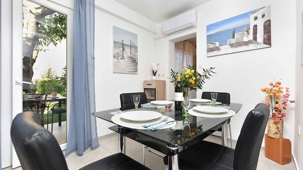 A dining area with a glass table, black chairs, and a vase of flowers. - Holiday apartment mit Klimaanlage und Terrasse (Porec)