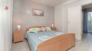 A bedroom with a wooden bed, bedside tables with lamps, a framed picture on the wall, and a door leading to an outdoor area. - Holiday apartment mit Klimaanlage und Terrasse (Porec)