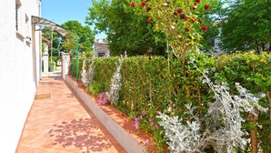 A garden pathway with a pergola, flowering plants, and a white building. - Holiday apartment mit Klimaanlage und Terrasse (Porec)