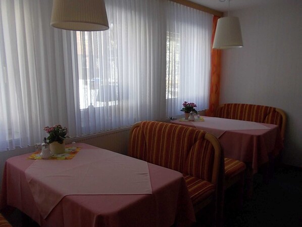 A dining area with two tables, each covered with a pink tablecloth, and striped chairs.