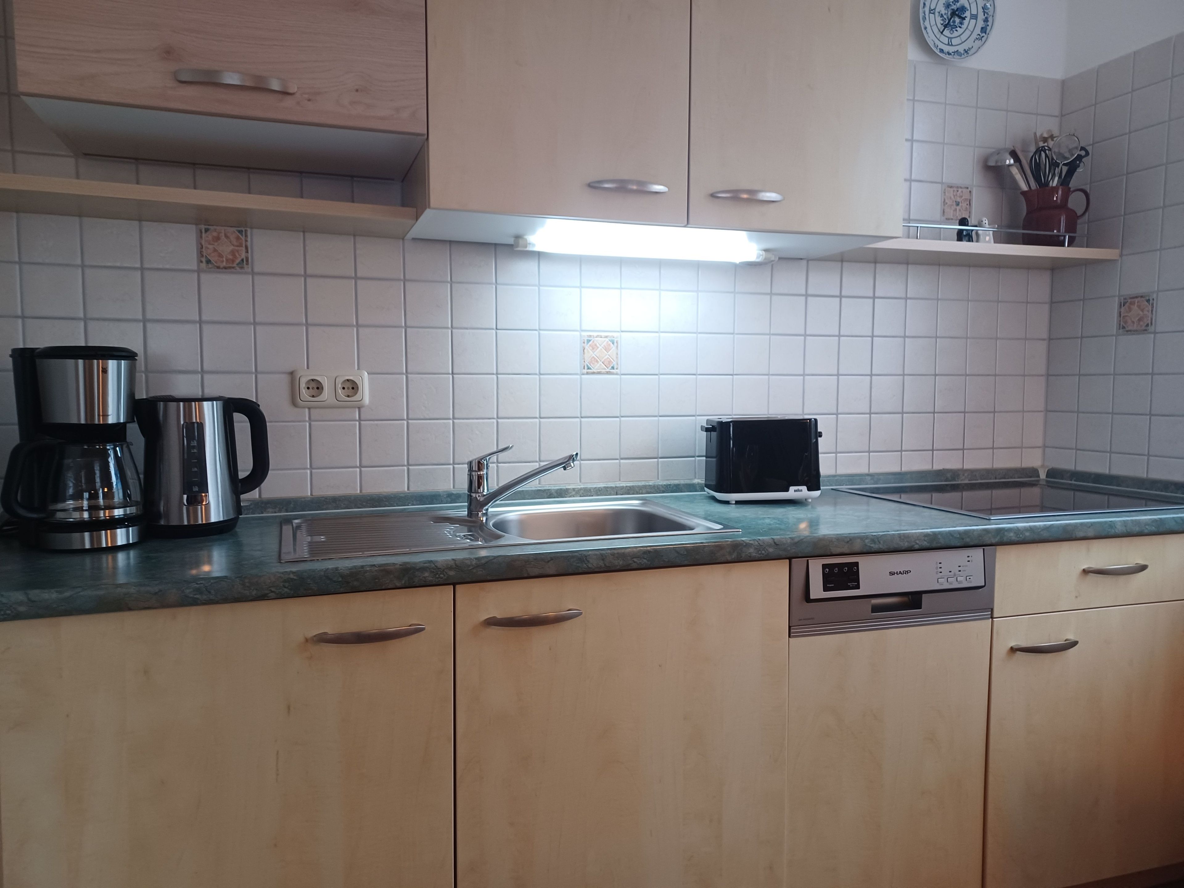 Eine Küche mit Spüle, Kaffeemaschine, Toaster und Schränken.