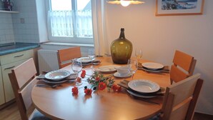 Een eettafel gedekt met borden, glazen en een vaas met bloemen.