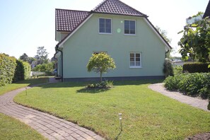 A two-story house with a tiled roof, a small tree in the front yard, and a paved pathway leading to the entrance. - At Sea, Starboard - At Sea - Starboard (Wustrow)