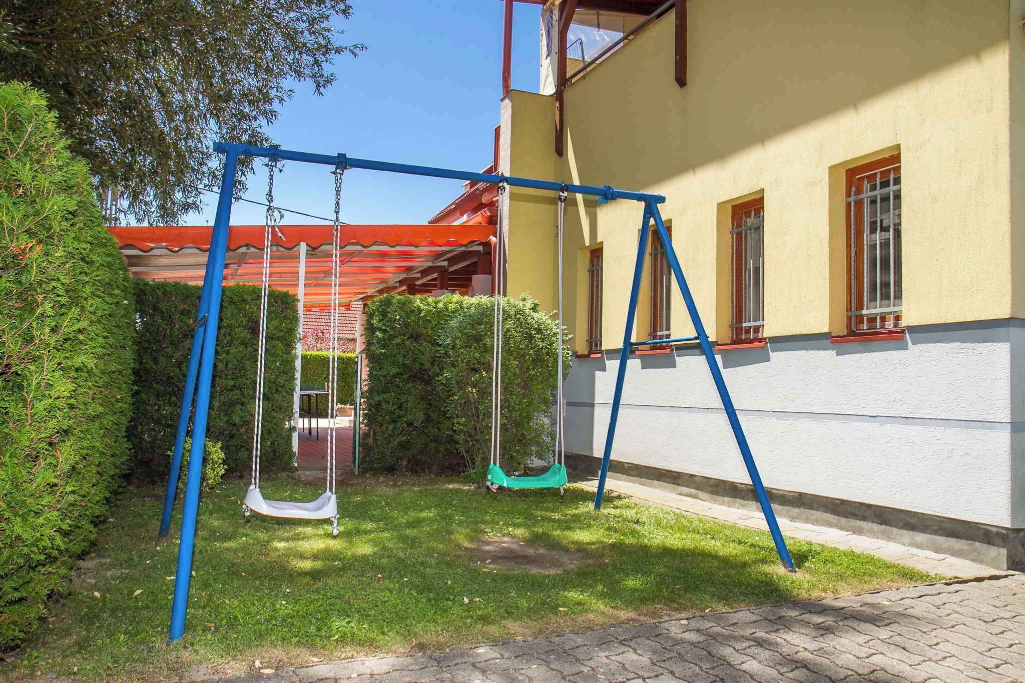 Un columpio en un patio trasero, con una casa al fondo.