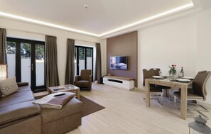 Un salon moderne avec un canapé, un téléviseur fixé au mur, une table à manger dressée pour deux personnes et une porte-fenêtre coulissante donnant sur un balcon.