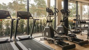 Un gimnasio con cintas de correr, elípticas y equipos de pesas.