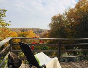 A wooden deck with a chair and a wooden bench, overlooking a forested hillside. - Vacation home Baumgarten1 - Holiday home Baumgarten 1 (Baumgarten bei Gnas)