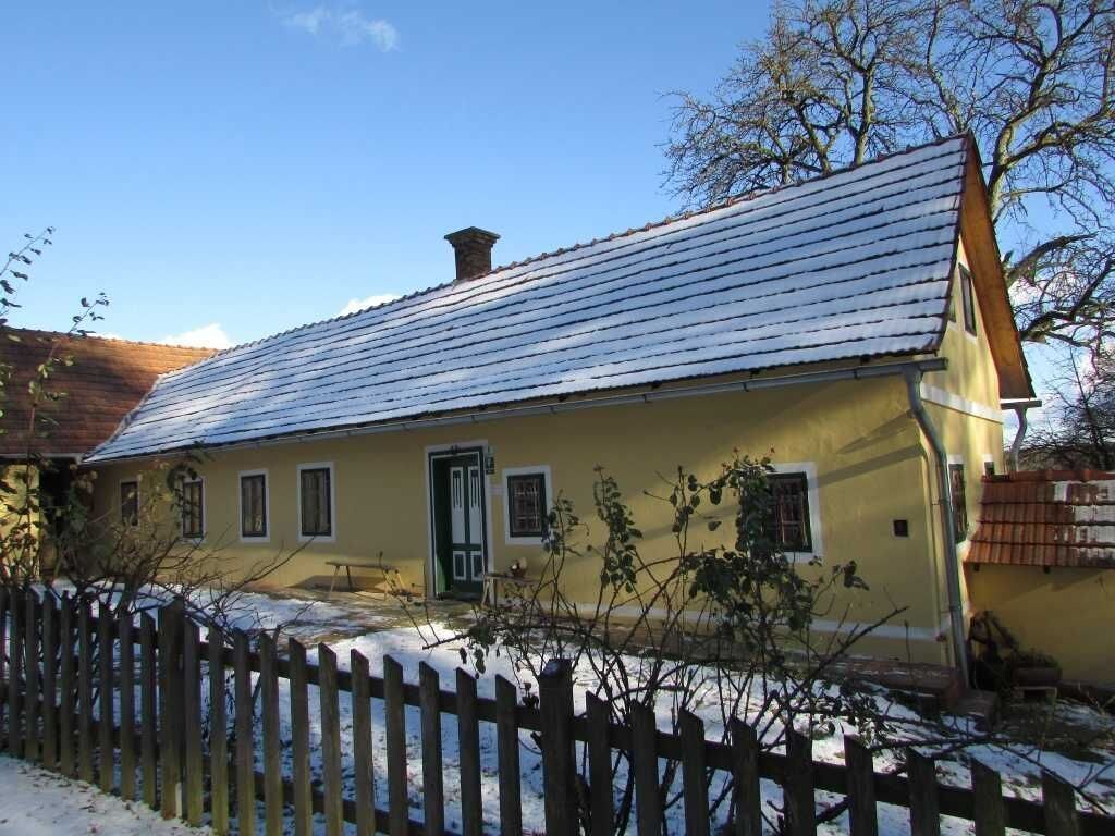 A single-story building with a sloped roof, a wooden fence in the foreground, and a clear sky.