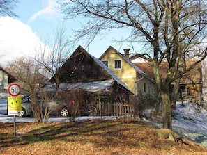 A yellow house with a sloped roof, a wooden fence, and a bicycle parked in front.