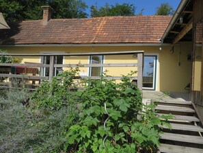 A yellow building with a tiled roof, a wooden fence, and a staircase leading to a door. - Vacation home Baumgarten1 - Holiday home Baumgarten 1 (Baumgarten bei Gnas)