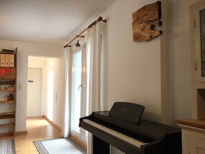 A piano in a room with a wooden shelf, a door with a curtain, and a wall-mounted wooden plaque. - Vacation home Baumgarten1 - Holiday home Baumgarten 1 (Baumgarten bei Gnas)