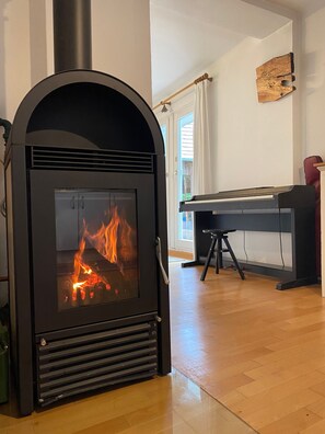 A room with a wood-burning stove, a piano, and a piano bench. - Vacation home Baumgarten1 - Holiday home Baumgarten 1 (Baumgarten bei Gnas)