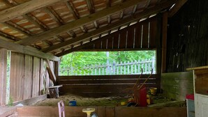 Ein rustikaler Innenraum einer Scheune mit Holzboden, einem kleinen Spielzeugauto und einem Fenster mit Blick auf Grünflächen.