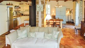 A cozy living room with a sofa, a dining table, and a kitchen in the background. - Pet friendly home in Ribaute (Ribaute)