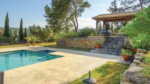 A swimming pool with a stone wall and steps leading to a pergola. - Pet friendly home in Ribaute (Ribaute)