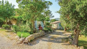 A gravel pathway leading to a stone wall with a rustic house in the background. - Pet friendly home in Ribaute (Ribaute)