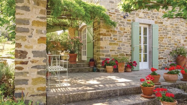 A stone building with a wooden bench and potted plants. - Pet friendly home in Ribaute (Ribaute)