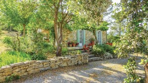 A stone house with a gravel driveway, surrounded by lush greenery and flowering plants. - Pet friendly home in Ribaute (Ribaute)
