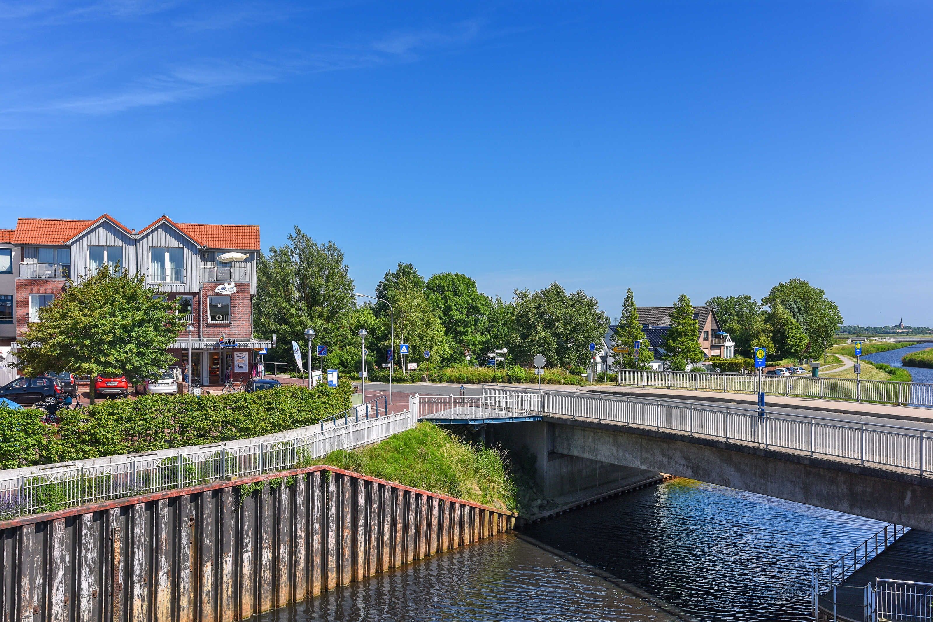 A canal-side view with a bridge, buildings, and greenery.