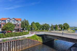A canal-side view with a bridge, buildings, and greenery. - Lee - house harbor view (Esens)
