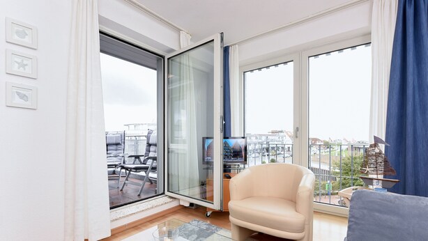 Un salon moderne doté d’une porte vitrée donnant sur un balcon, d’un canapé, d’une table basse et d’un téléviseur.